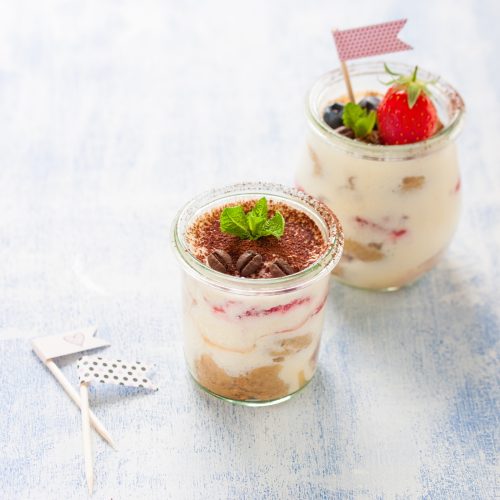 close-up-delicious-desserts Homemade italian dessert tiramisu with strawberries, mint and cocoa in glass jars, closeup