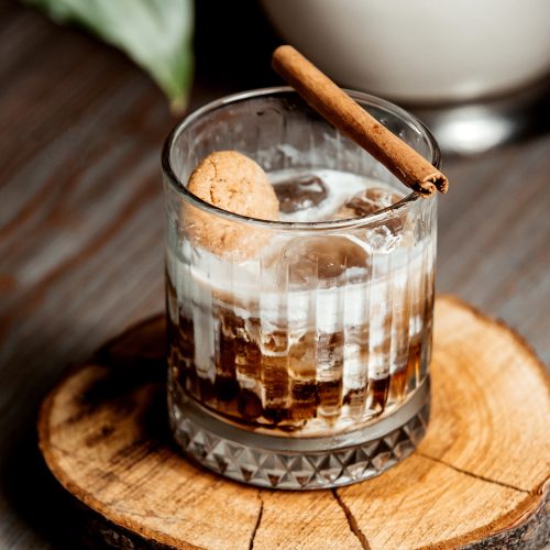 a glass of iced coffee cocktail garnished with cinnamon stick